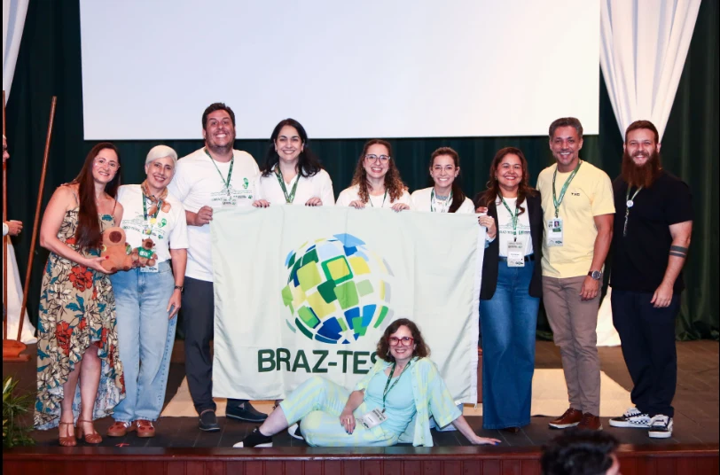 Conference community gathered on stage with the BRAZ-TESOL flag